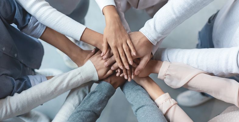 Multiracial business team putting hands on top of each other