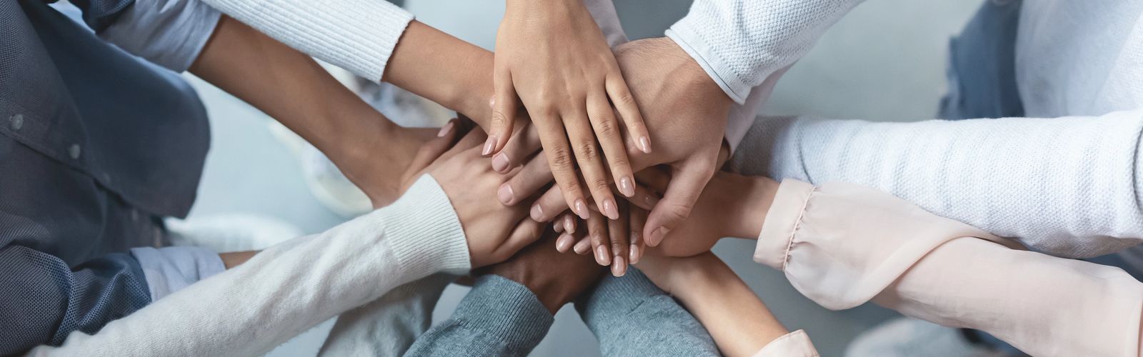 Multiracial business team putting hands on top of each other